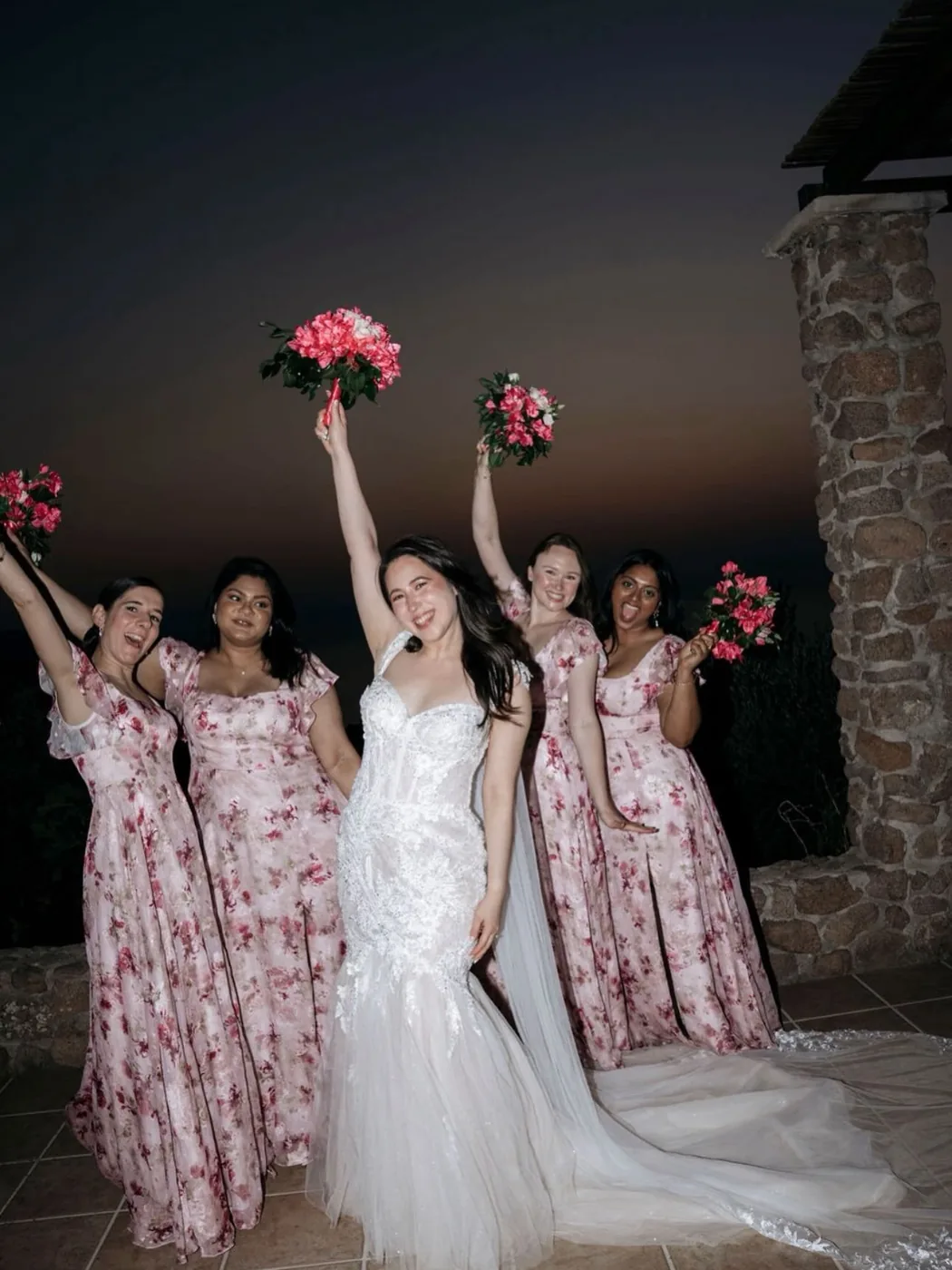 The bride and her bridesmaids by the stone wall after dark